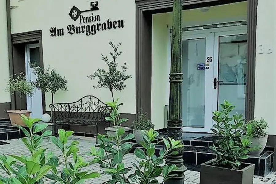 Fassade der Pension am Burggraben in Hinte, mit Schild und Terrasse